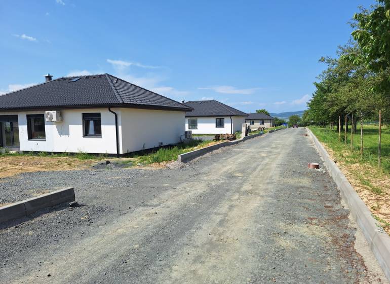 Family houses on Vyšná Šebastová Street in Prešov surrounded by greenery, next to an unfinished road.