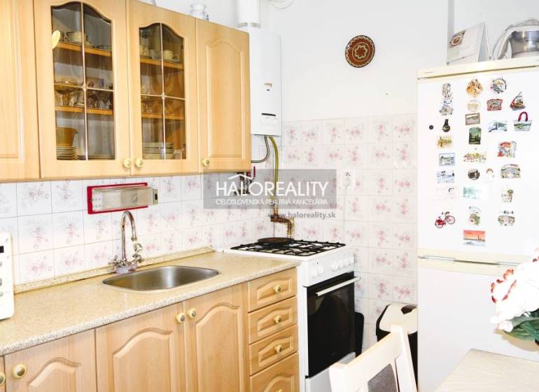 A kitchen in a 3-room apartment with wooden decor, a microwave, and a refrigerator.