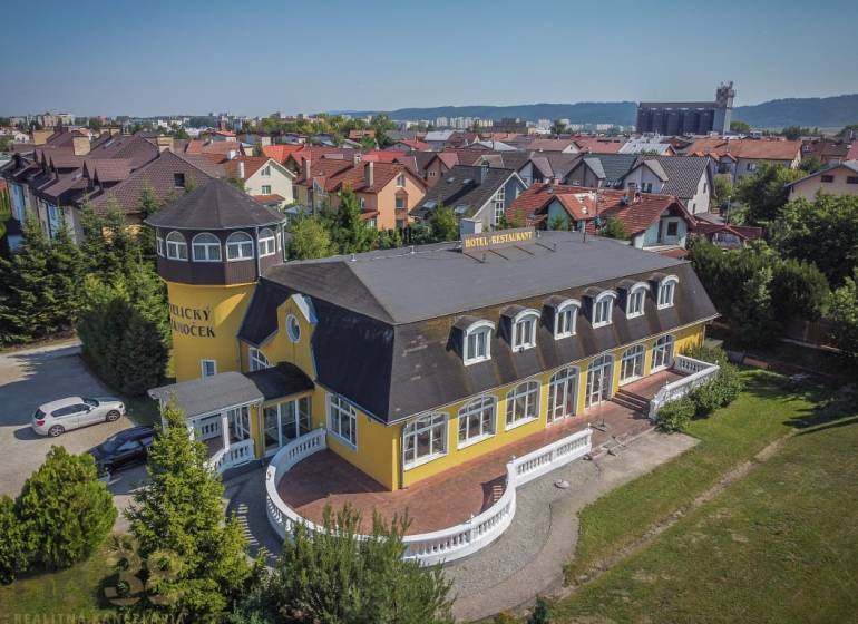 Yellow hotel with a tower, surrounded by a garden in the city of Poprad, hotels and guesthouses.