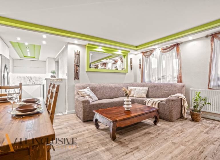 Living room in a family house with a wooden decor floor and green details on the ceiling.