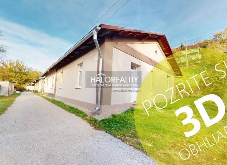 A family house in Sirk with a long facade, green lawn, and an access road on the side.