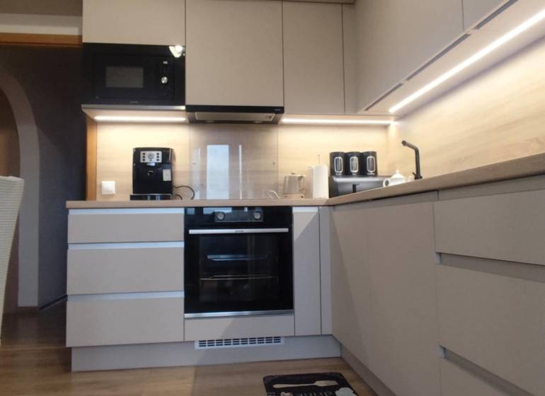 A kitchen in a 3-room apartment with a wooden decor floor and built-in appliances.