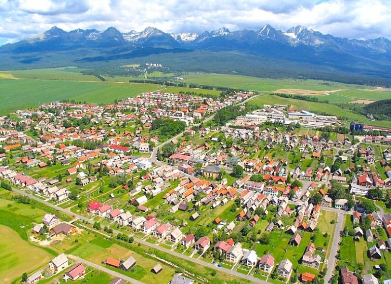 Aerial view of agricultural and forest land in Štrba with the High Tatras in the background.