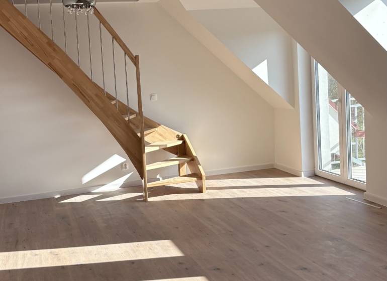 Attic space in a 3-room apartment with a wooden decor floor and a staircase.