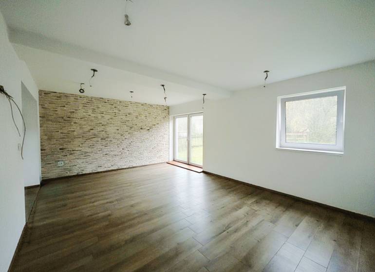 A spacious living room with a stoneware wall and a wooden decor floor in a family house.