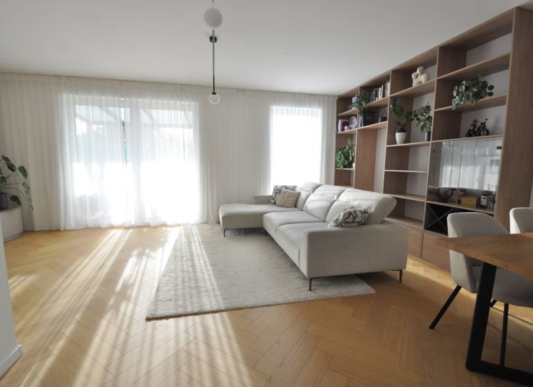Living room of a family house with a bookshelf, sofa, and wooden decor flooring.