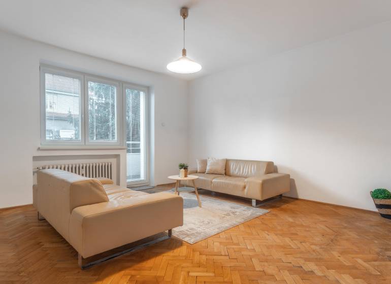 Living room in a three-room apartment with beige sofas and a wooden decor floor.