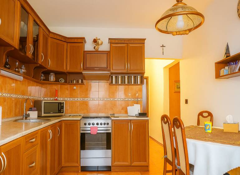 A kitchen in a 2-room apartment with wooden cabinets and a dining table.