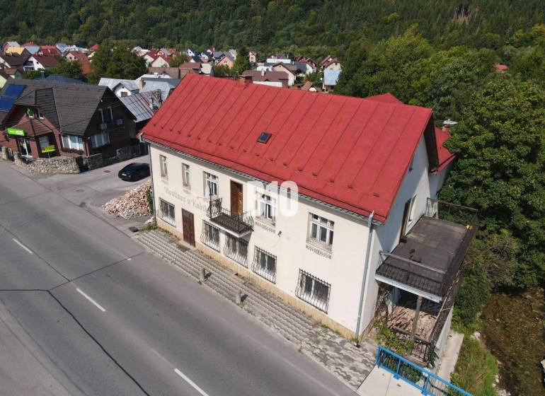 A building in Belá with a red roof, surrounding houses and nature.