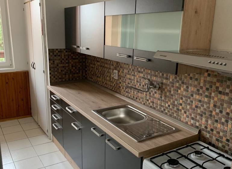 A kitchen in a 2-room apartment with mosaic tiles and a gas stove.