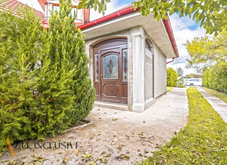 A family house in Bátorove Kosihy with glazed doors and ornamental conifers.