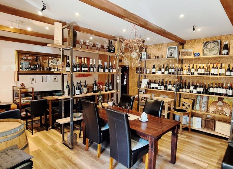 Interior of commercial premises with wood-decor flooring, full of wine bottles and wooden elements.