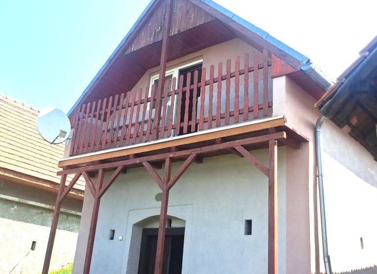 A cottage in Hontianske Trsťany with a wooden balcony and a satellite dish.