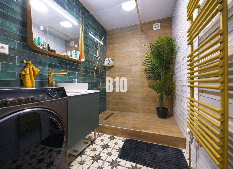 Bathroom in a 3-room apartment with a sink, washing machine, green tiles, and a floor with a wooden decor.