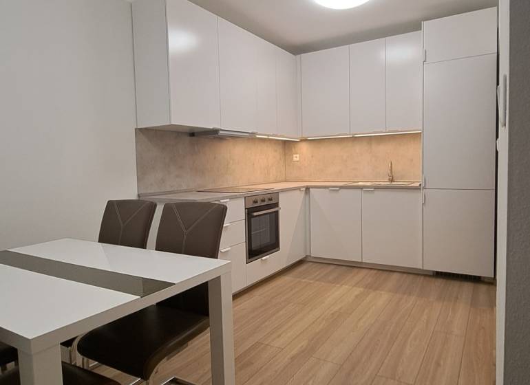 A kitchen in a 2-room apartment with white cabinets and a wood-patterned floor.