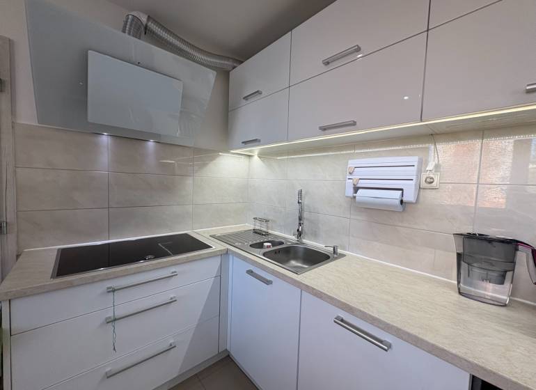 A kitchen with a built-in cooktop and sink in a 3-room apartment.
