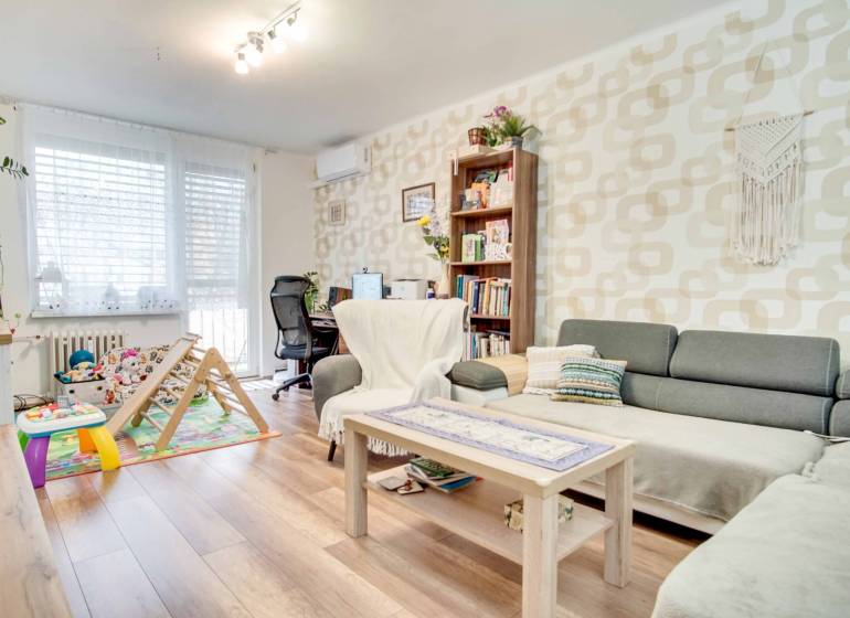 Living room in a three-room apartment with a wooden decor floor and a work corner.