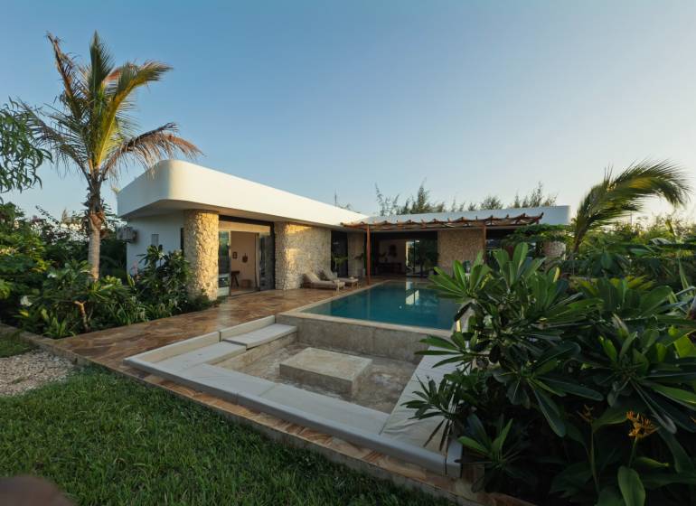 A family house in Paje, Unguja South Region with a pool, surrounded by lush vegetation and paving.