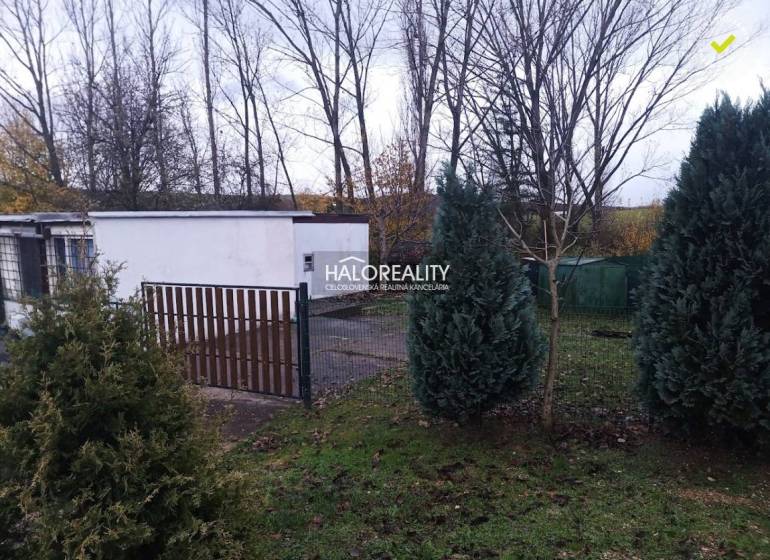 Recreational plots in Nitrianske Rudno, trees, bushes, and fencing near the white building.