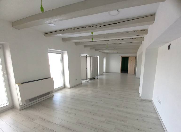 White office with wood-patterned flooring, decorative beams, and light-colored walls.