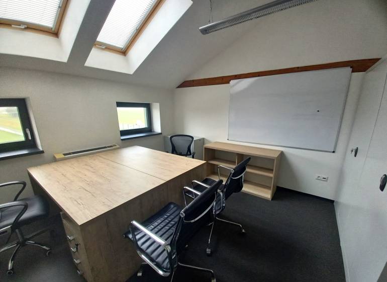 Office with chairs, a whiteboard, a table with a wooden decor, and skylights.