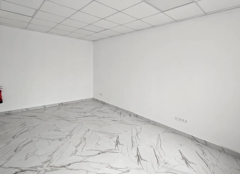 Commercial premises with a marble floor and a fire extinguisher by the wall.
