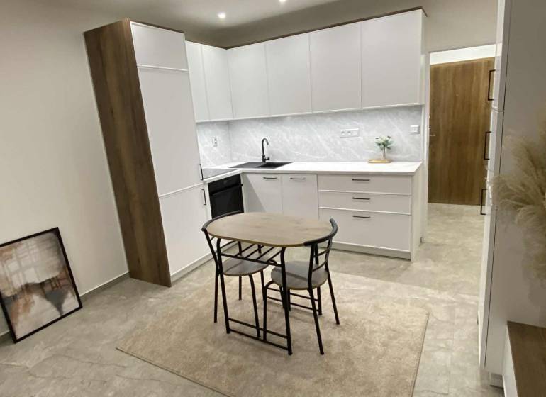 A kitchen in a studio apartment with white cabinets and a dining table.