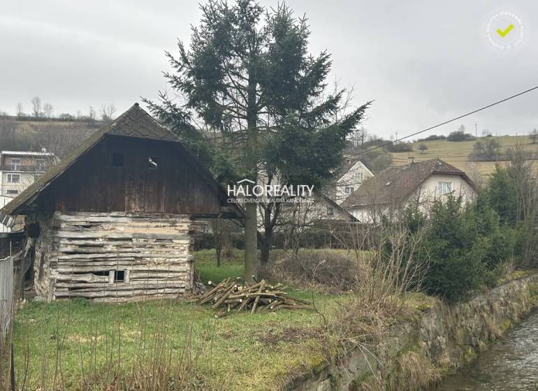 A wooden cottage by the stream, surrounded by trees, grass on the property - living in the countryside.