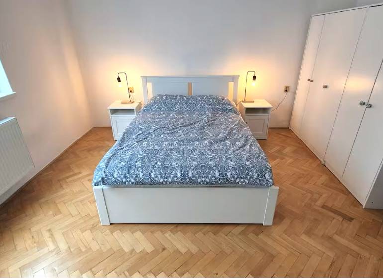 Bedroom with a bed, nightstands, and a wardrobe, floor with wood decor.