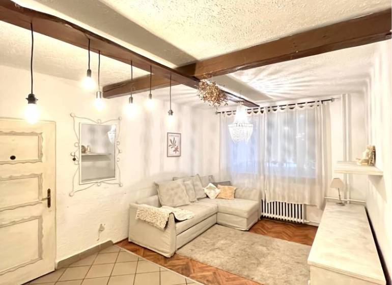 Living room with wood-patterned flooring in a 3-room apartment, white sofa and curtains.