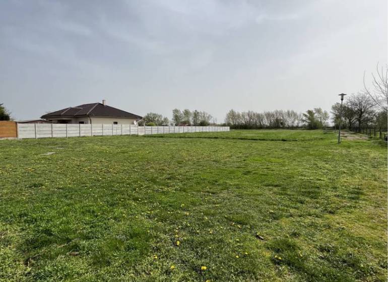 Green plots in Komárno suitable for living, with grassy surface and fencing.