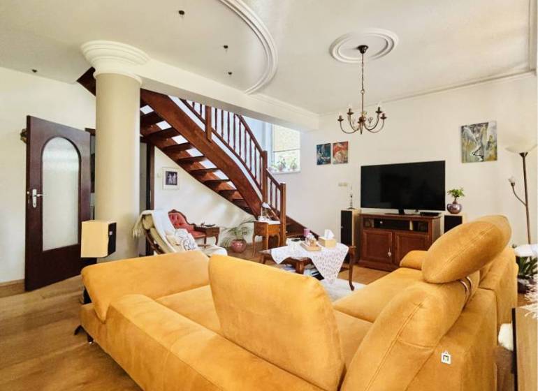 A family house with a wooden decor floor, staircase, sofa, and television.