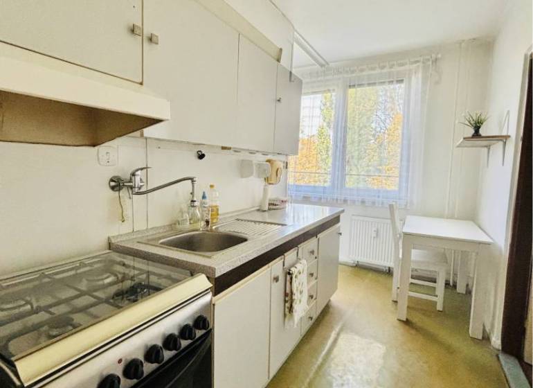 A kitchen in a 2-room apartment with a gas stove and a dining area.