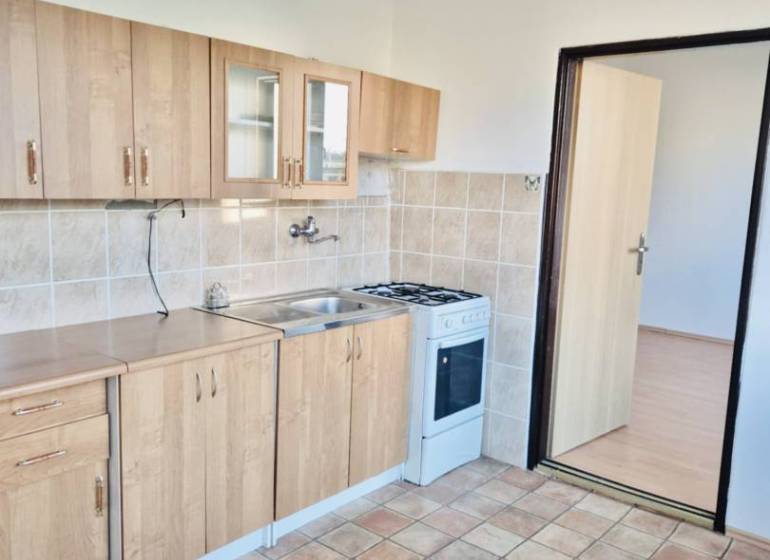 Kitchen in a studio apartment with tiled flooring and wooden decor cabinets.