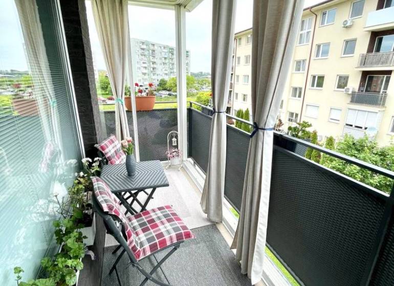 The balcony of a 2-room apartment in Dunajská Streda with garden furniture and flowers.