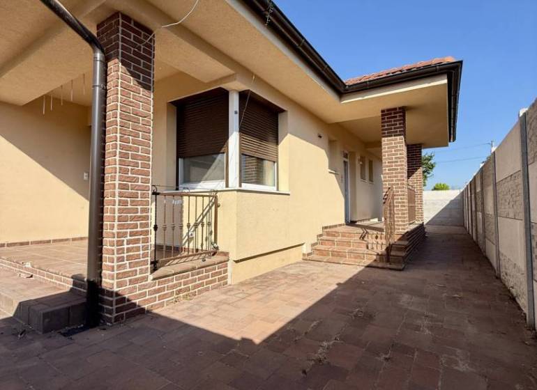 A family house in Okoč with brick details and a paved courtyard.