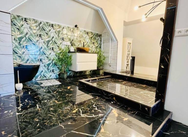 Luxurious bathroom with black marble and green vegetation design elements in a family house.
