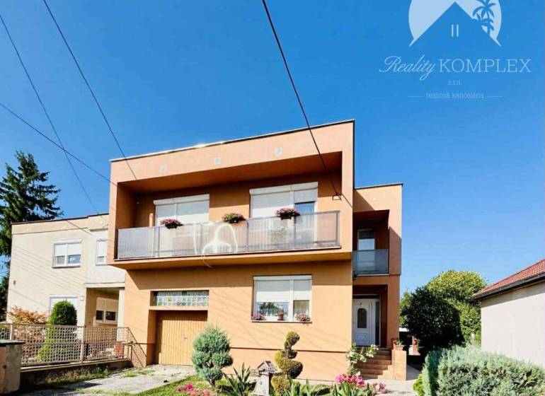 A family house in Okoč with a garden and a balcony under the blue sky.