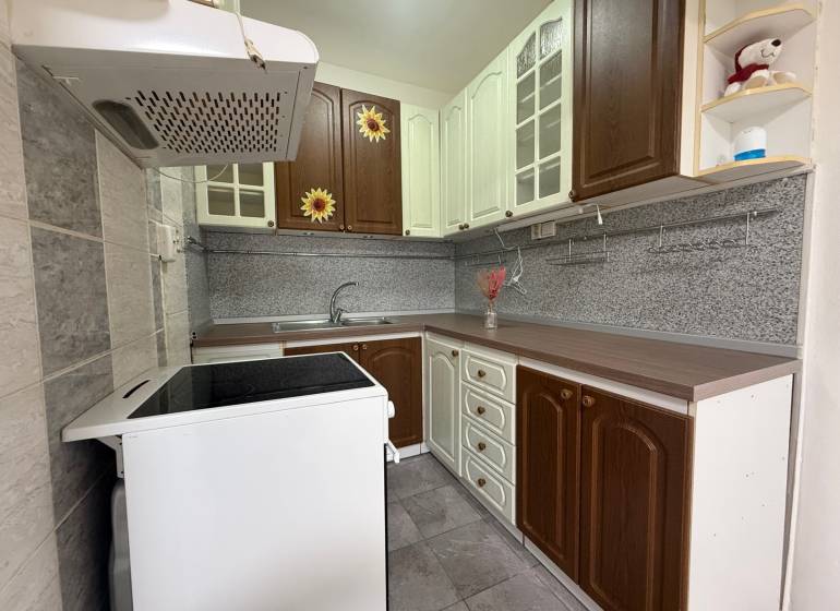 A kitchen in a 2-room apartment with dark brown and white cabinets and a stainless steel countertop.