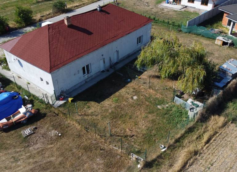 A family house in Zemianska Olča with a red roof, lawn, and boat trailers in the yard.