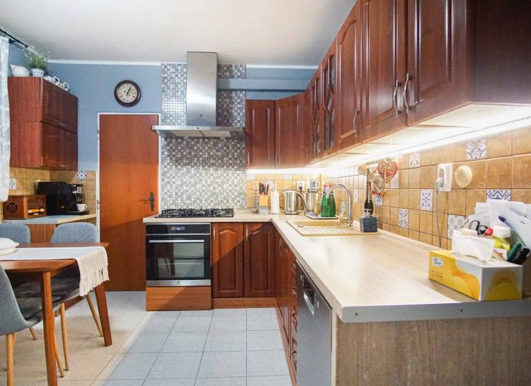 A kitchen in a 3-room apartment with wooden cabinets and a dining table.
