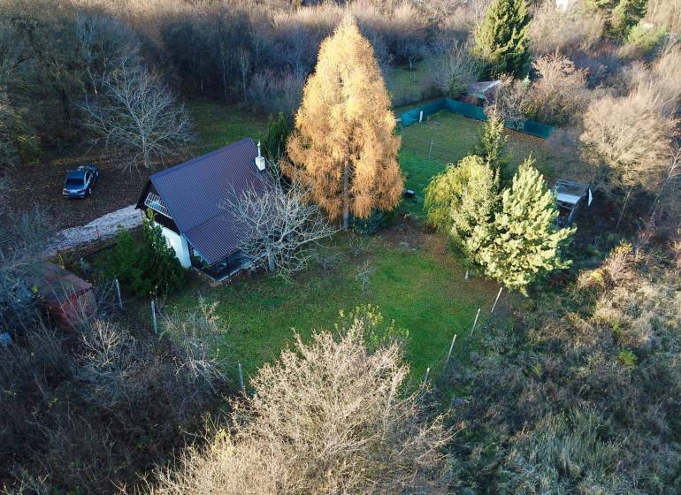 A cottage in Štitáre surrounded by greenery and trees, with a car on the driveway.