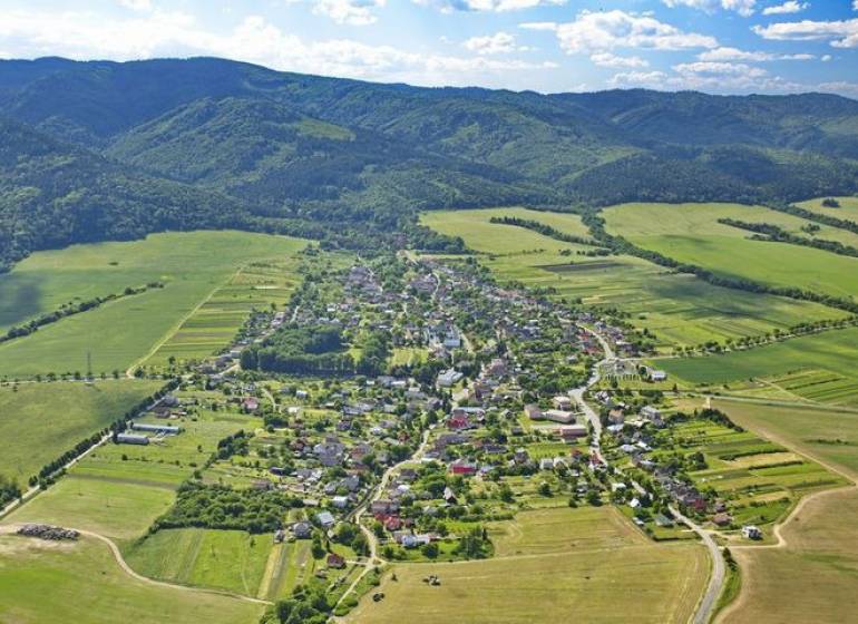 Aerial view of agricultural and forest land around Hertník surrounded by forests.