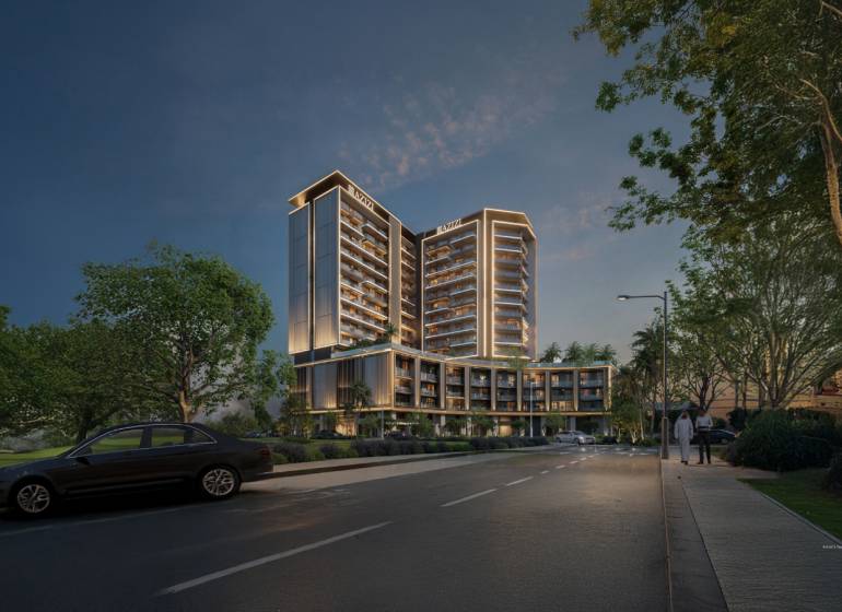 Night scene of a building in Downtown Jabel Ali, illuminated trees and a parked car.