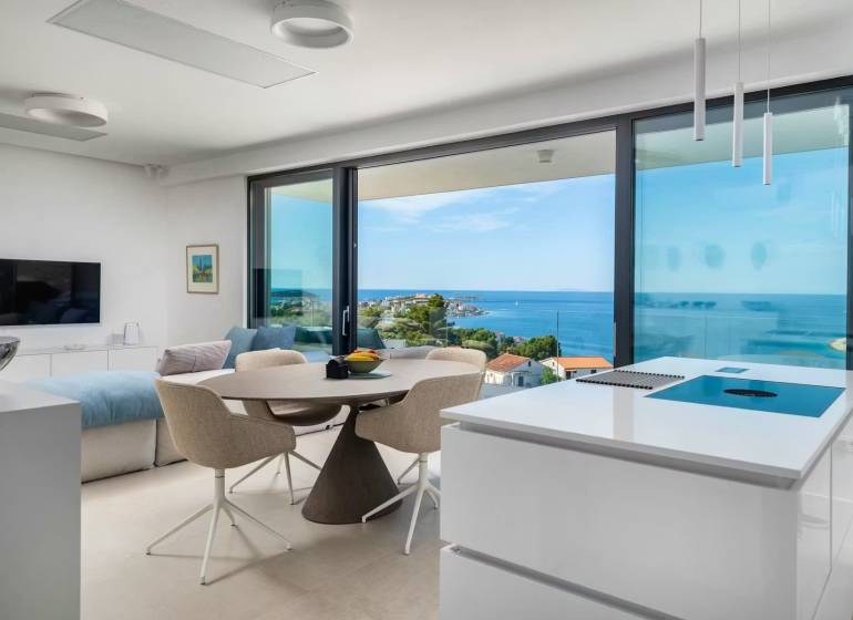 A holiday apartment with a sea view, bright interior with large windows and a kitchen island.