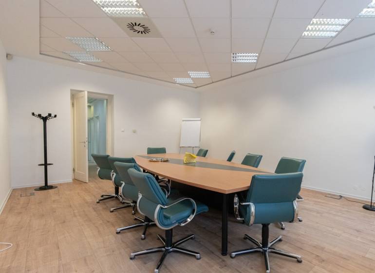 Conference room with wood-patterned flooring, a round table, and green chairs.