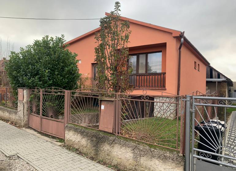 A family house in Lúčnica nad Žitavou with an orange facade, a garden, and a decorative fence.