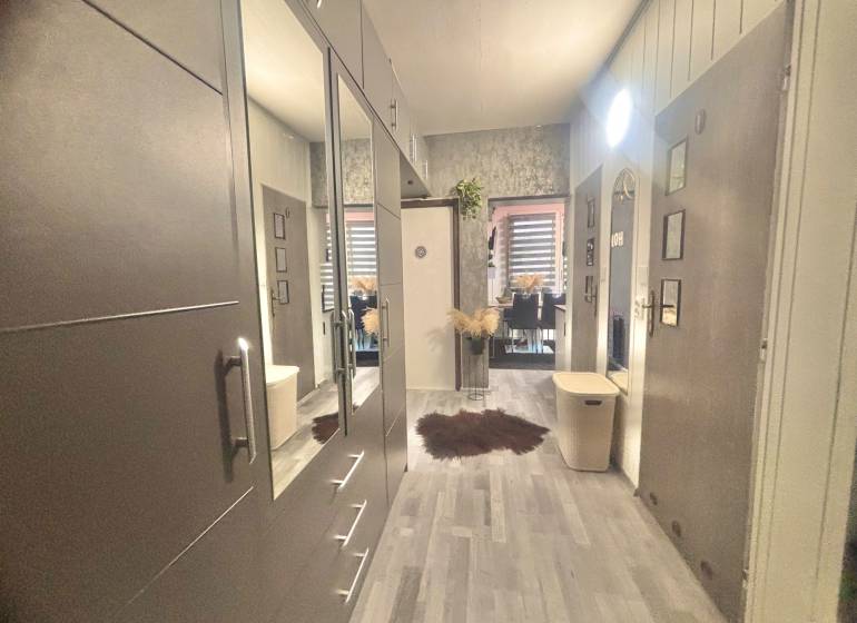 A hallway with a wooden decor floor in a 3-room apartment leading to the dining room.