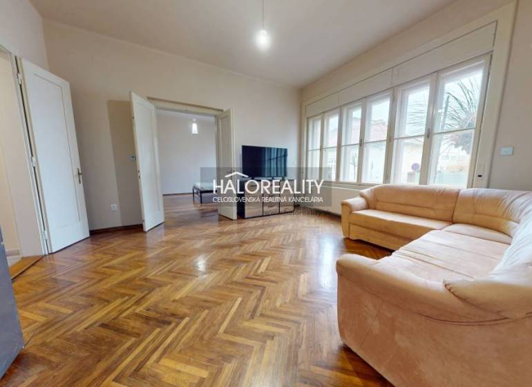 Living room of a three-room apartment with a sofa and a wooden decor floor.