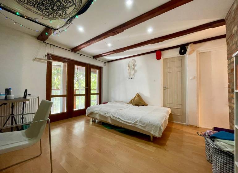 Interior of a cabin with a bed, chair, and floor with wooden decor.